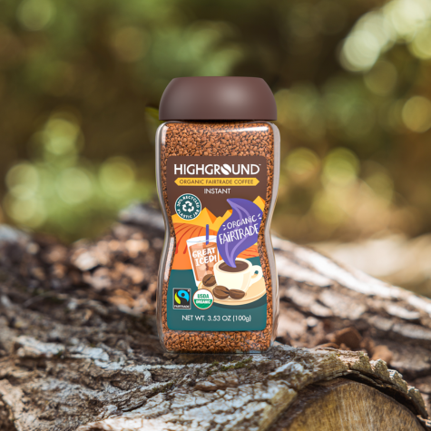 A jar of Fairtrade, medium roast, organic, instant coffee from Highground nestles amid tree roots on a forest floor.