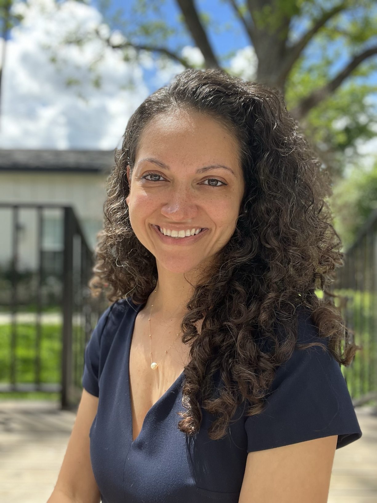 Portrait of Kenzel Fallen, Co-Founder and CEO of Three Keys Coffee. She stands in front of a tree a wrought iron fence.