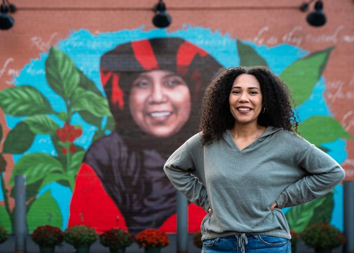 Artist Julia Bottoms stands in front of her mural of coffee farmer Ibu Rahmah.