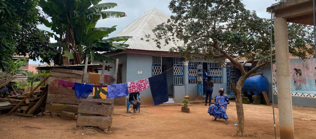 A nearly swept, packed dirt courtyard, a line of colorful laundry and a blue home.