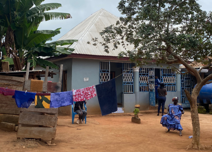 A nearly swept, packed dirt courtyard, a line of colorful laundry and a blue home.