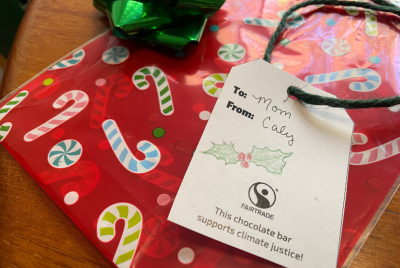 A kitchen table covered with gift wrapping materials. A gift tag is shown with the Fairtrade logo and reads: 