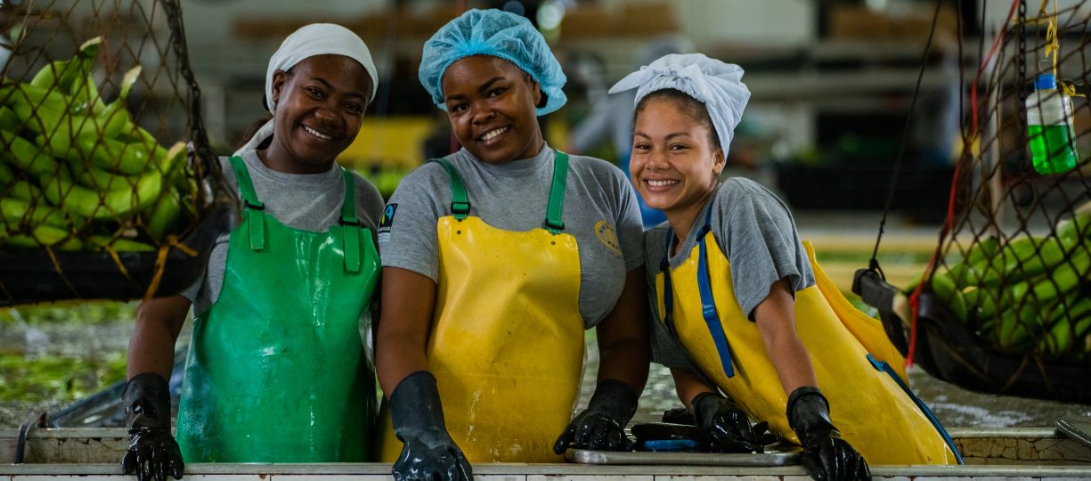 A group shot of three young women working in a banana processing plant.